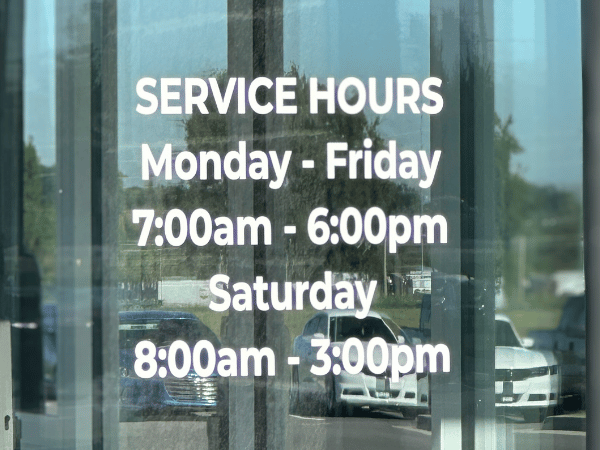 Front window with store hours at Crain Kia of Fort Smith
